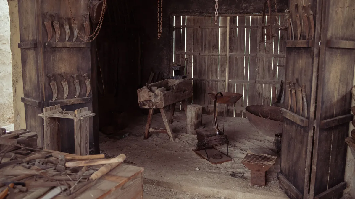 A blacksmith's workshop with various tools and equipment, including a workbench, anvil, and hammer.