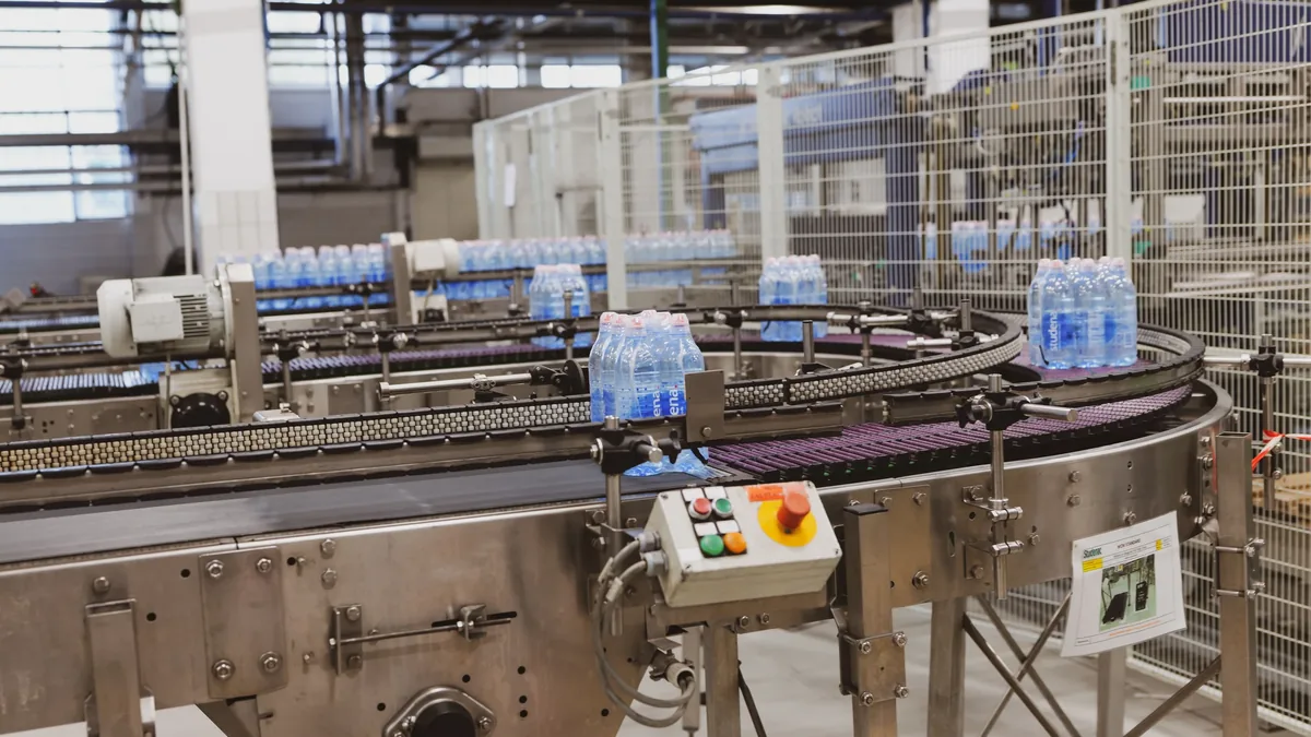 A large industrial machine with a conveyor belt and bottles of water on it, likely used in a manufacturing or packaging facility.