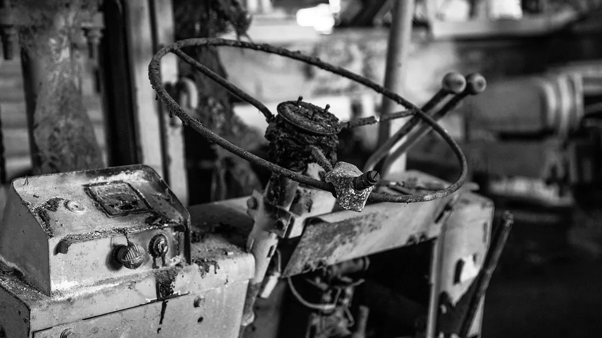 A close-up view of an old, rusty metal machine with a large wheel and a control panel.